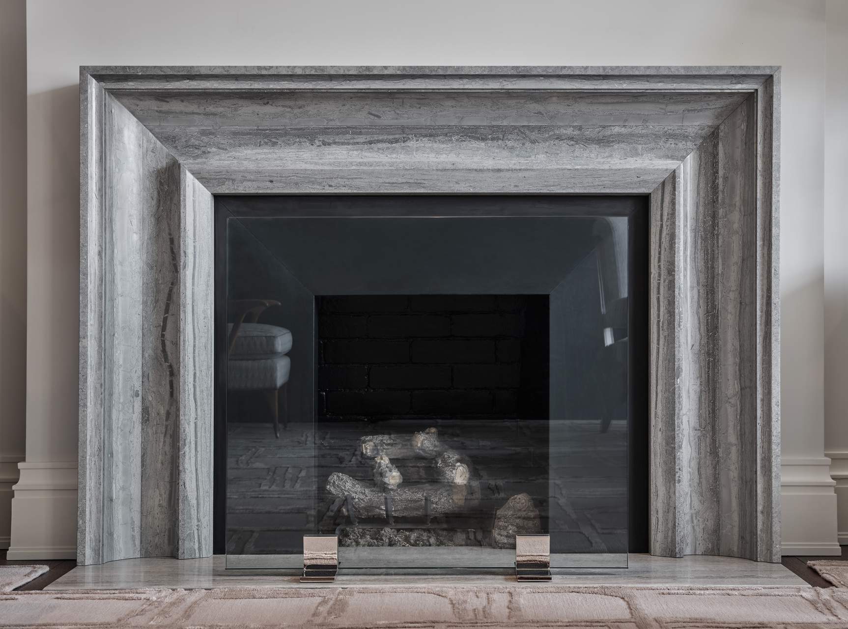 Gray stone fireplace mantel and surround with layered profiles, angled inner faces, and a matching hearth.